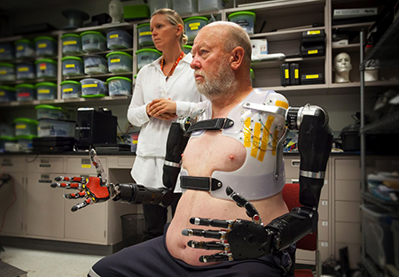 APL prosthetist Courtney Moran looks on as Les Baugh tests out the Modular Prosthetic Limbs. (Image courtesy of Johns Hopkins University Applied Physics Laboratory)